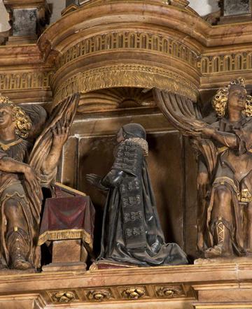 Carved wooden figure of person in long robes at a lectern
